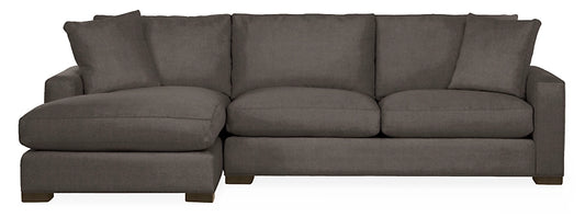 The Metro Sofas with Chaise, featuring a gray color and L-shaped design, includes thick cushions and two pillow accents, set against a white background.