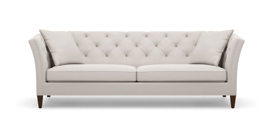 The Shelton 98" Sofa is a light gray tufted sofa with two cushions, showcasing a modern design with angled armrests and dark wooden legs, set against a white background.