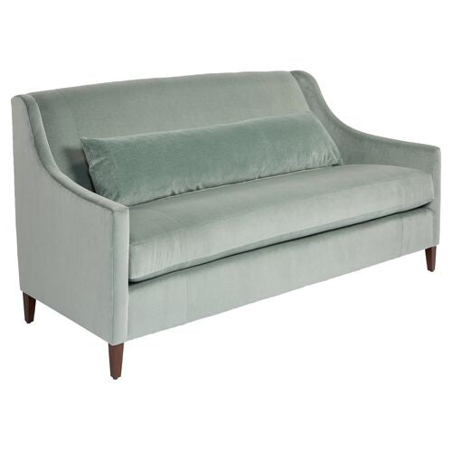 The Dawes Sofa in Sage Velvet is displayed, featuring a sleek and modern design with a matching long lumbar pillow and tapered wooden legs that create an elegant appearance.