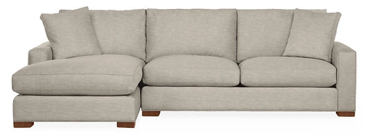 The Metro Sofas with Chaise is a light gray sectional featuring three seat cushions and three back cushions. It includes a chaise on the left side and is supported by wooden legs, making it suitable for a modern living room.