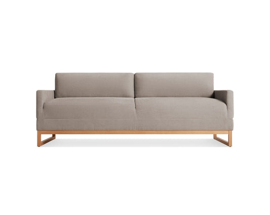 A modern, minimalist gray upholstered sofa with a wooden frame and low-profile armrests, seated on a rectangular wooden base. The sofa has two back cushions and a sleek, contemporary design.