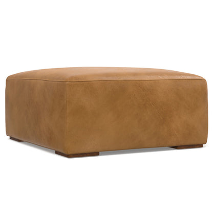 Tan leather ottoman with a square shape, featuring a smooth, cushioned top and low-profile legs, set against a plain white background.