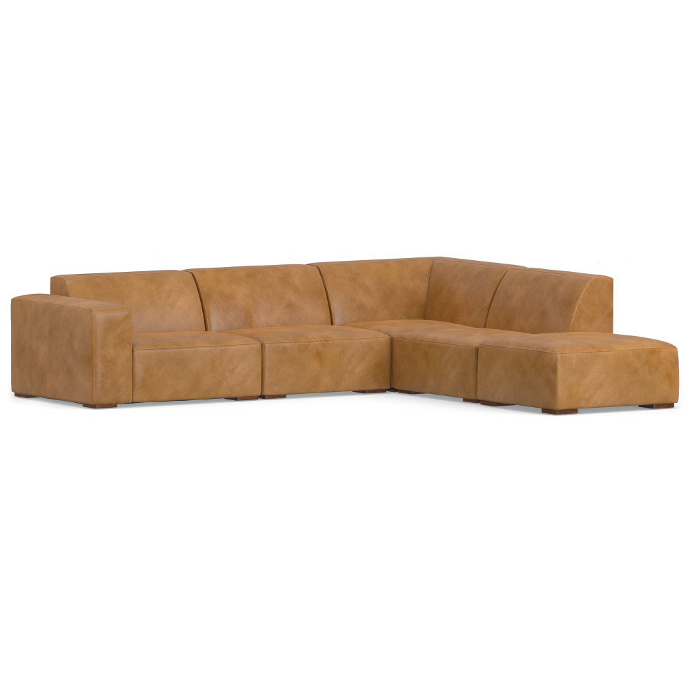 A large, L-shaped sectional sofa in light brown leather. It features clean lines and block-style cushions, with a modern and minimalist design. The sofa rests on small legs, giving it a low-profile appearance.