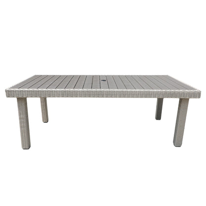 The Balcones Wicker Rectangular Dining Table has a slatted wooden top, four corner legs, and a central hole for an umbrella. It features a wicker-style frame and comes in light gray.