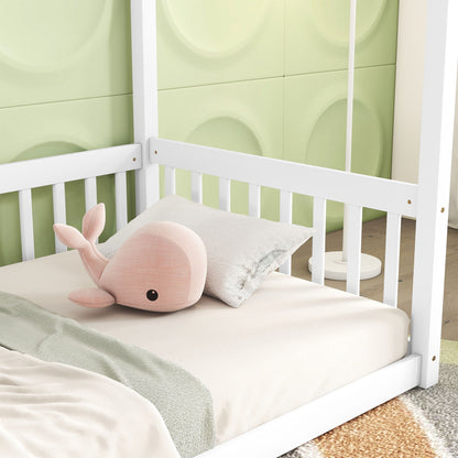 The Canopy Frame Floor Bed With Fence features a white frame and is adorned with light beige bedding, a pink plush whale, and a light gray pillow. The background showcases green geometric wall panels.