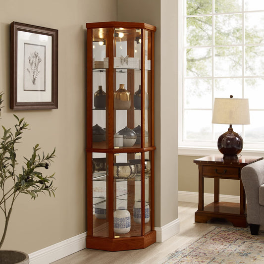 The 6 Shelf Lighted Corner Curio Cabinet, with adjustable tempered glass shelves and a mirror back, displays decorative pottery. It's set in a well-lit room with beige walls, a framed floral picture, a nearby table lamp, a small sofa, and a potted plant. Note: E26 light bulb not included.