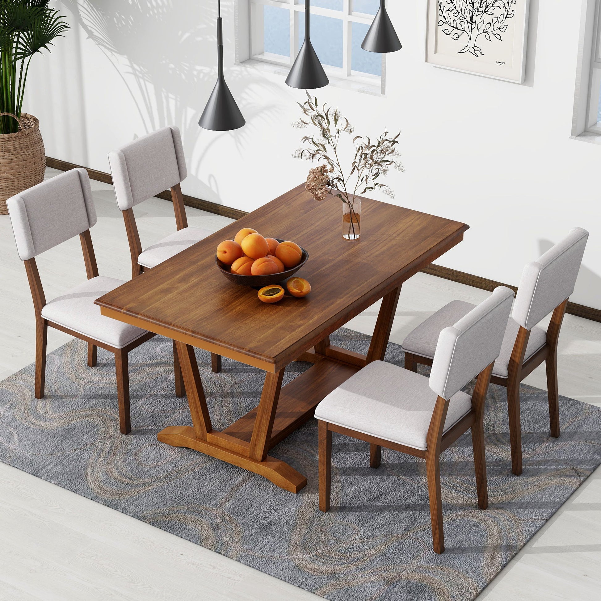 The Topmax 5 Piece Rustic Dining Table Set with a rectangular trestle table base is adorned with a bowl of oranges. Four upholstered chairs surround it, illuminated by two pendant lights above. A plant sits in the corner, with windows and a painting in the backdrop, all atop a patterned rug.