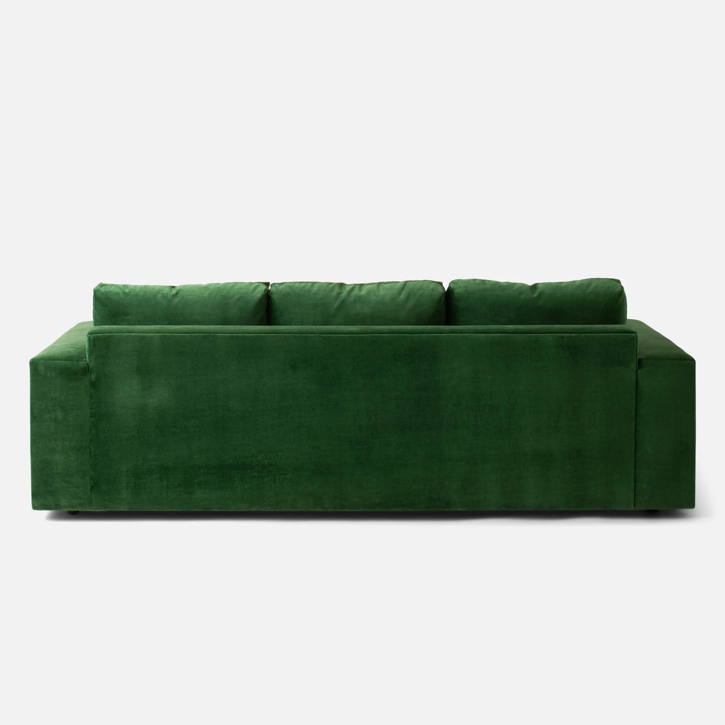 The luxurious Marc Tufted Sofa, upholstered in plush green velvet, is displayed from the back against a simple white background. It features a modern design with three prominent seat cushions on top.