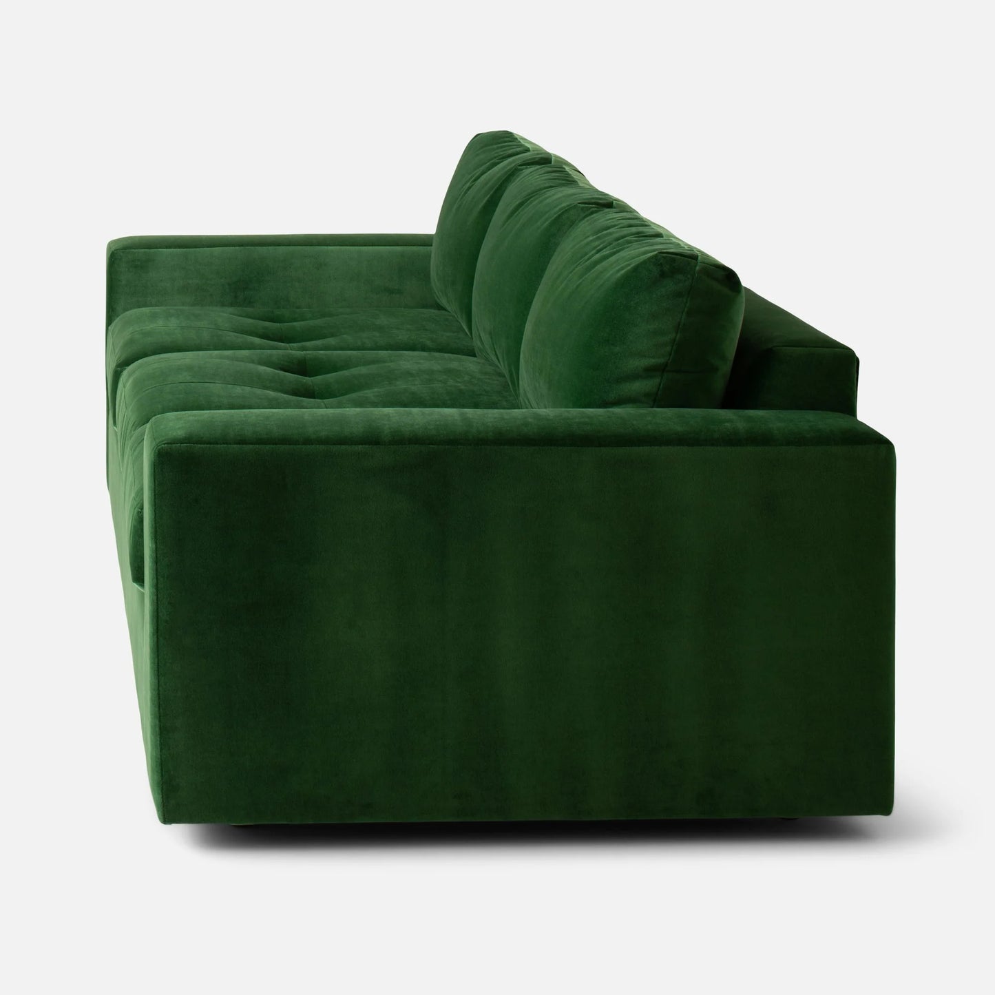 Side view of the Marc Tufted Sofa, featuring a modern, deep green velvet design with plush cushions and clean lines set against a plain white background.