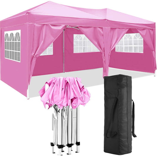 A 10'x20' pink portable canopy tent is set up with its folded frame and a black carrying bag, featuring six removable sidewalls with clear windows.