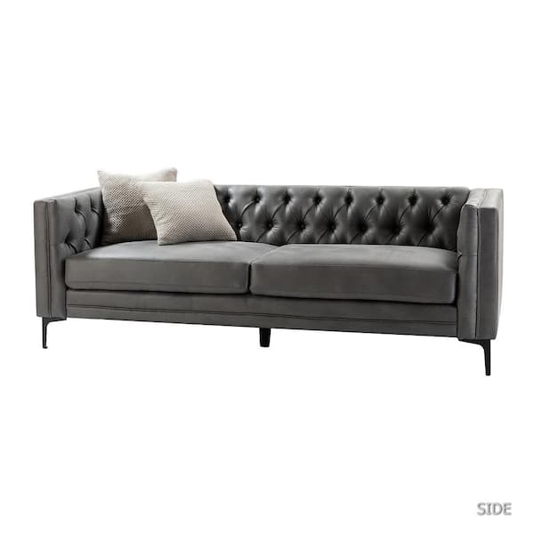 The JAYDEN CREATION Eridu Contemporary 84 in. Square Arm Sofa in Camel is an elegant piece with a button-tufted design featuring a faux leather finish. It is complemented by slender black legs and comes with two decorative pillows in light gray and beige.