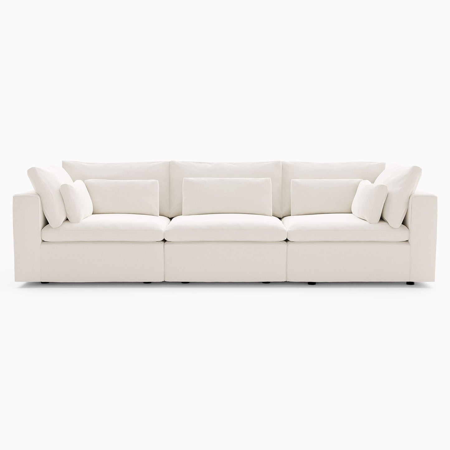 The Harmony Modular 3 Piece Sofa is a white, contemporary sectional displayed on a white background. It features four spacious seat cushions, a straight back, and several accent pillows, offering a clean and minimalist appearance.