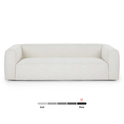 The Cigar 92" Leather Sofa in Rawhide Tan is displayed against a pristine white backdrop. Beneath the sofa, a firmness scale showcases its balanced support, offering a perfect blend of softness and firmness.