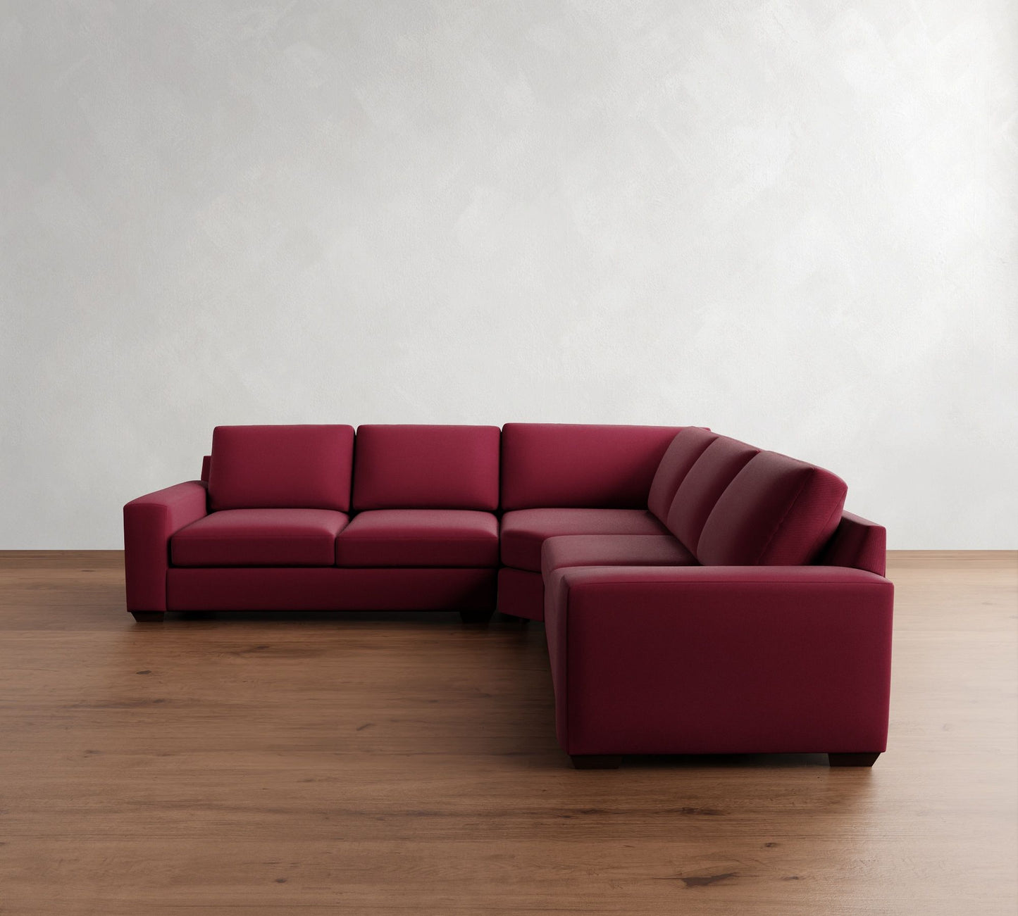 The Big Sur Square Arm Upholstered 3-Piece L-Shaped Wedge Sectional in red features clean lines and is positioned on a polished wooden floor against a textured white wall, forming a cozy corner seating area.