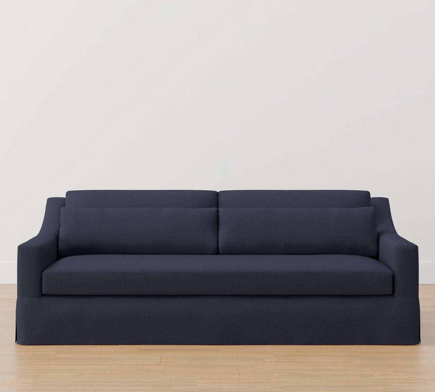 The York Slope Arm Deep Slipcovered Sofa in dark gray rests on a light wooden floor against a plain white wall. With its two large back cushions and sleek, modern design, it offers a minimalist aesthetic.