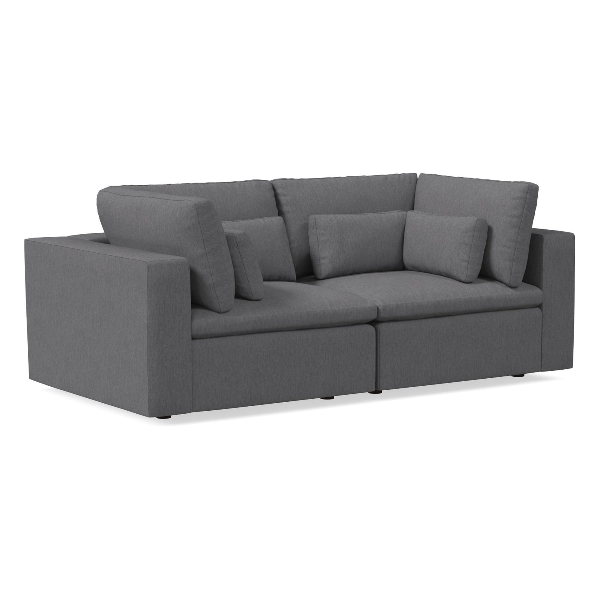 The Harmony Modular 3 Piece Sofa, a modern sectional in dark gray with thick cushions and armrests, adorned with multiple pillows for enhanced comfort, is set against a white background.