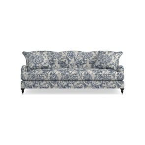 Introducing the Sanderson x Giles Deacon Bedford 87" Sofa, showcasing a captivating floral pattern in shades of blue and white. This sofa boasts cushioned seating and backrest, elegant curved armrests, and is supported by dark wooden legs. Its design is accentuated by intricate fabric detailing.