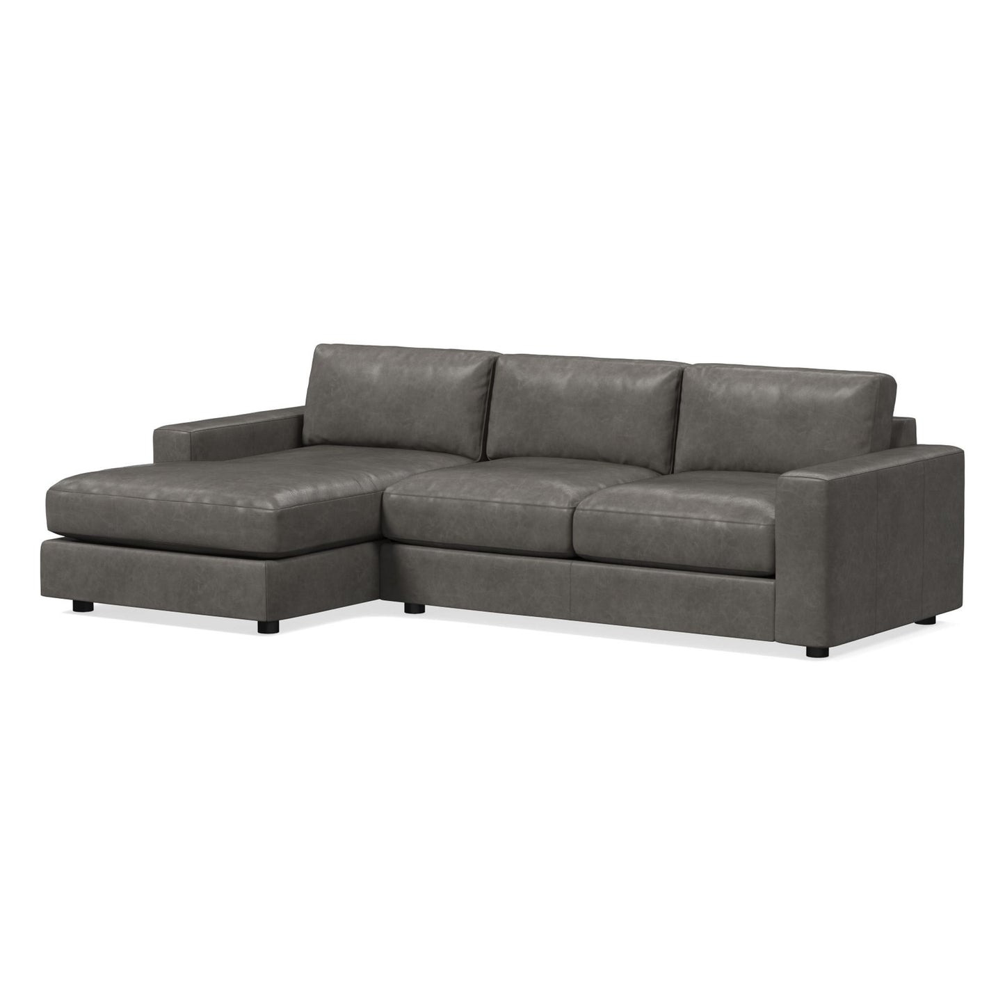 The Urban Leather 2 Piece Chaise Sectional is a contemporary gray sectional couch with sleek lines and a chaise lounge positioned on the left side. It includes three back cushions and rectangular armrests, crafted from a smooth, leather-like material and supported by short black legs.