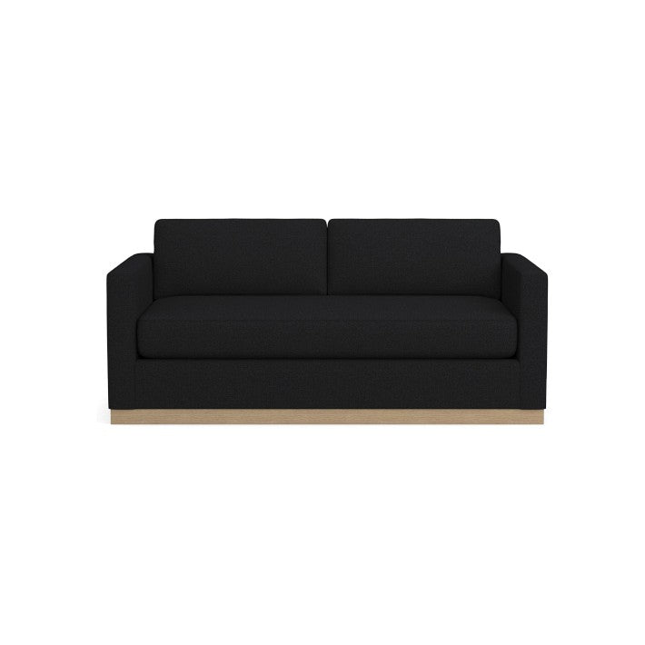 The Valencia 72" Loveseat is a modern black sofa with a minimalist design, featuring clean lines and a wooden base. It includes rectangular cushions and armrests, set against a plain white background.