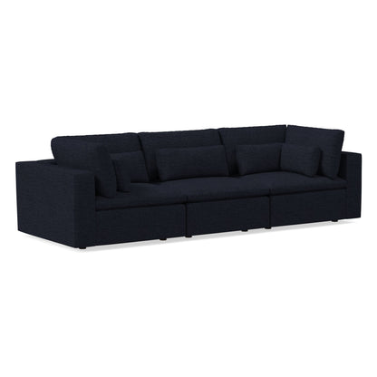 The Harmony Modular 3 Piece Sofa showcases a dark, modern aesthetic with a minimalist design. It features multiple cushions and a deep, plush seat that complement its rectangular shape and clean lines, all set against a plain background to emphasize its sleek appearance.