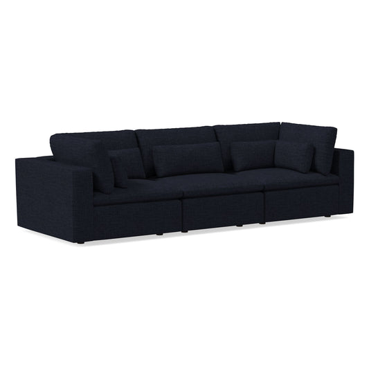 The Harmony Modular 3 Piece Sofa showcases a dark, modern aesthetic with a minimalist design. It features multiple cushions and a deep, plush seat that complement its rectangular shape and clean lines, all set against a plain background to emphasize its sleek appearance.