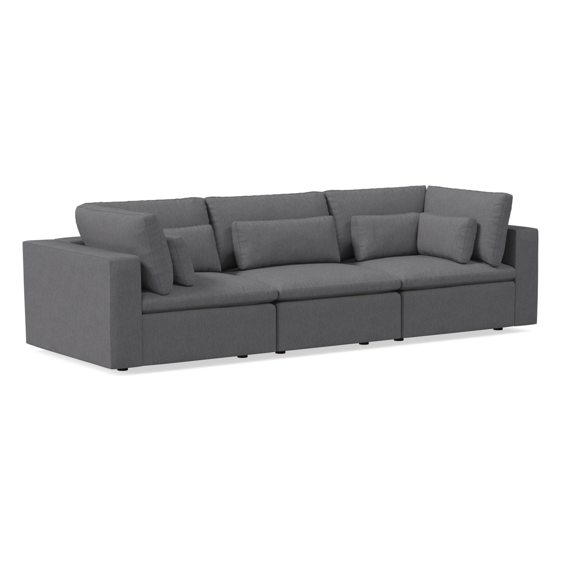 Introducing the Harmony Modular 3 Piece Sofa: a contemporary grey sectional with plush cushions and three seats, designed with blocky armrests and two accent pillows for added style. Its smooth-textured fabric is complemented by low, discreet legs.