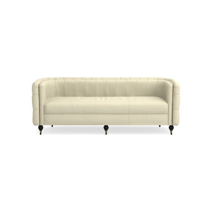 The Soho Sofa is a beige, tufted leather piece featuring black legs on a white background. It boasts a rounded back and armrests, presenting a classic and elegant design.