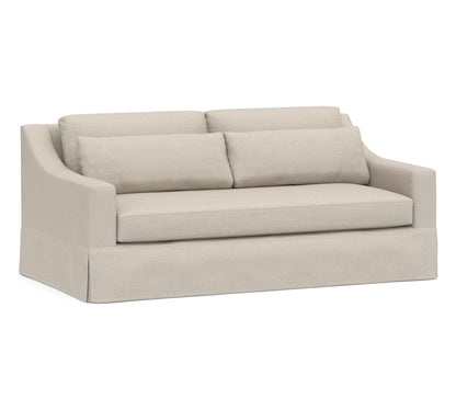 Introducing the York Slope Arm Deep Slipcovered Sofa: This elegant piece features a soft beige fabric, complemented by two plush back cushions and a single seat cushion. Its skirted base and gently curved backrest lend a cozy, modern aesthetic to any living space.