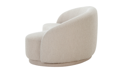 The Excelsior Sofa Cream features a plush, modern design with a rounded, curved backrest and a smooth, textured fabric in beige. It is supported by a matching circular base that complements its sleek and contemporary aesthetic.