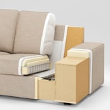 Cutaway view of the KIVIK Sofa in beige with light wood accents, highlighting its internal structure, including cushions, frame, and springs. The image provides a detailed look at parts of the armrest and base against a plain background.