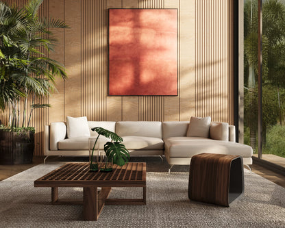 A modern living room features the Reade Sectional Sofa in beige accompanied by a wooden coffee table with a plant on top and complemented by a distinctive wooden stool. A large abstract red painting adorns the wood-paneled wall, while tropical plants are visible through the expansive floor-to-ceiling windows.