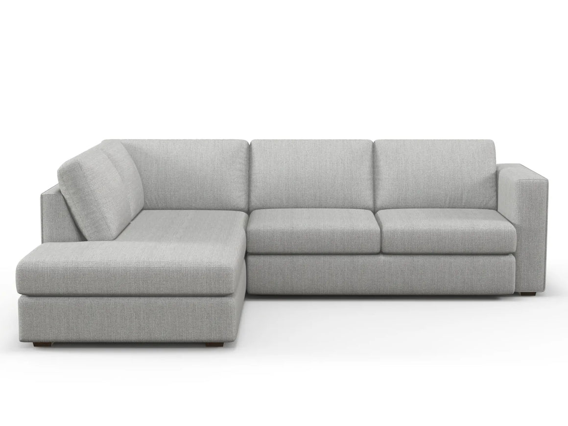 Introducing the Lounge Bumper Sectional, a contemporary gray sofa with sleek lines, complemented by a left-side chaise. This minimalist design offers plush cushions and is showcased against a crisp white background.