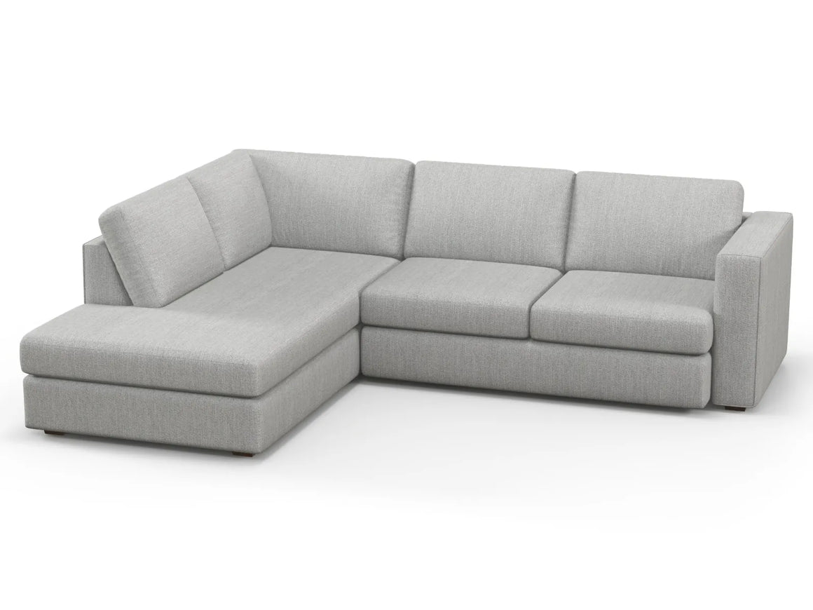 The Lounge Bumper Sectional is a gray L-shaped sectional sofa featuring a chaise on the left side. With its clean lines and plush cushions, it offers a modern and comfortable seating option. The fabric feels soft yet durable, making it ideal for a contemporary living room.