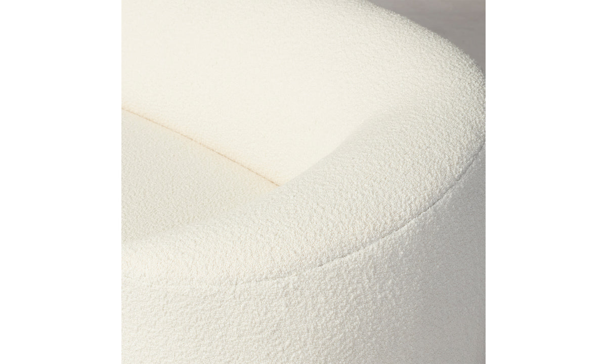 Close-up of the top corner of a rounded Chelsea Sofa in Italian Bouclé White. The bouclé fabric looks soft and plush, with a gentle curve that creates an inviting appearance. The neutral background accentuates the sofa's design.