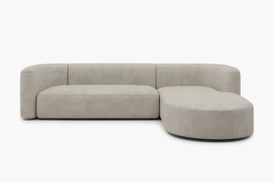 The Mellow Sectional Sofa by Acanva is a contemporary, minimalist beige sectional with a right-side rounded chaise. It showcases sleek, clean lines and a luxuriously cushioned surface, positioned against a simple white backdrop.