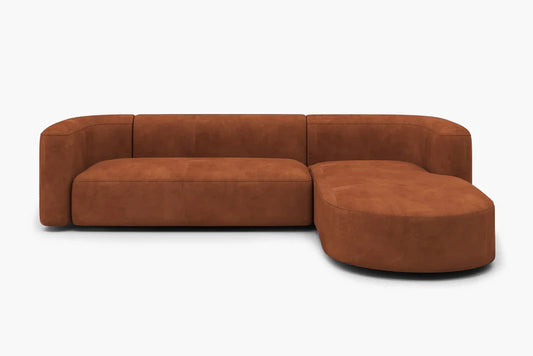 The Mellow Sectional Sofa by Acanva is a contemporary brown suede L-shaped design with plush cushions and a rounded chaise end, showcased against a plain white background.