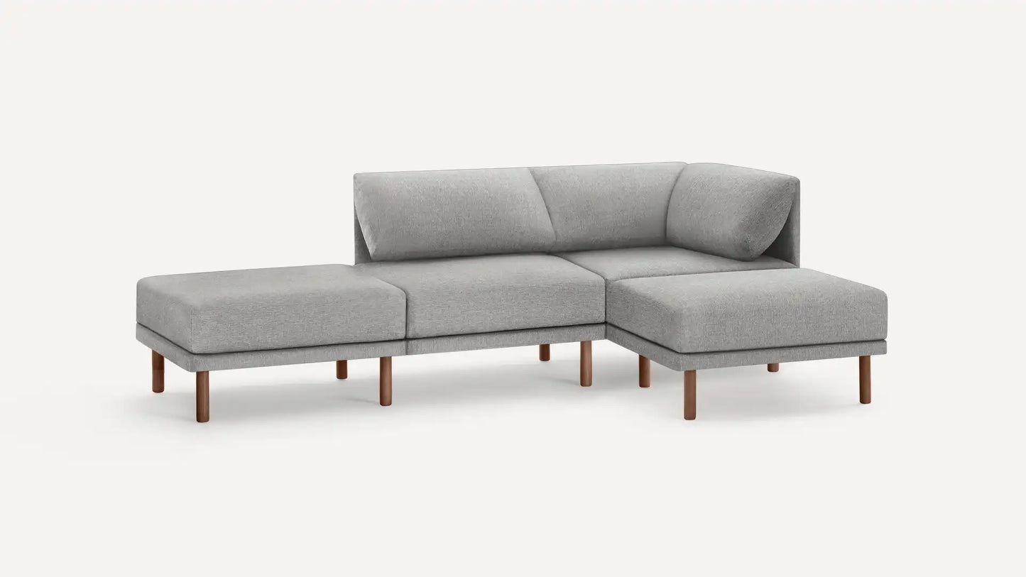 The Range Fabric 4-Piece Open Sectional Double Lounger Sofa is a modern piece in light gray, featuring three seats and an extended chaise lounge on the left. It boasts wooden legs and a minimalist design against a plain white background.