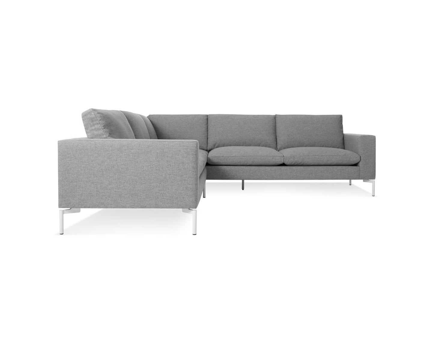 A New Standard Sofa Sectional Sofa in a modern gray color is displayed, featuring a minimalist design with square cushions and white metal legs for a clean and sleek appearance. The sofa is set against a plain white background.