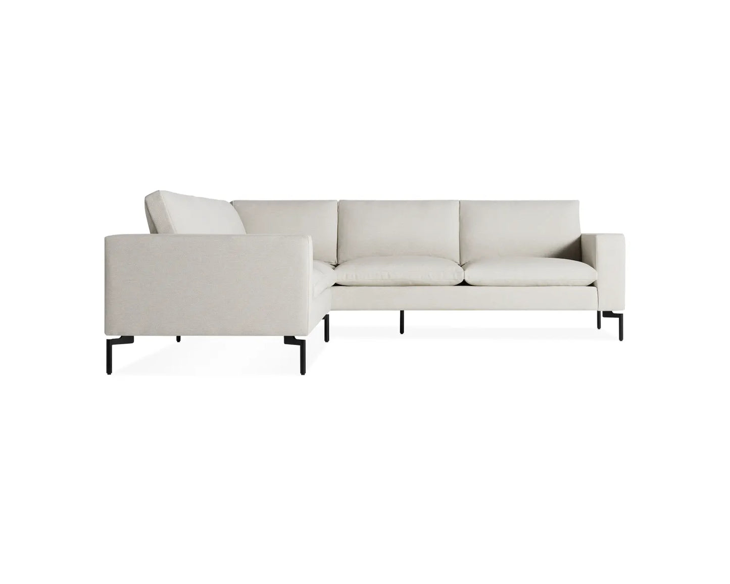 The New Standard Sofa Sectional features a contemporary minimalist L-shaped design, upholstered in light beige fabric, with slim black metal legs, set against a plain white background.