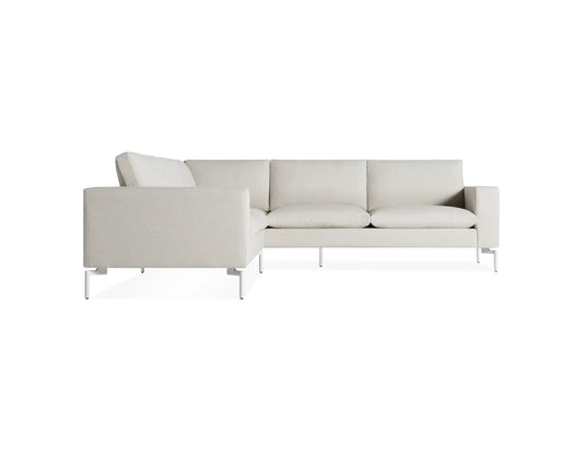 The New Standard Sofa Sectional features a modern L-shaped design with light gray upholstery and sleek metal legs, set against a plain white background.