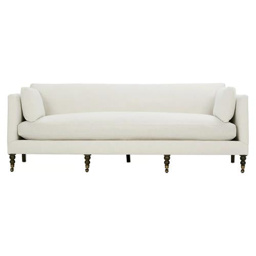 The Madeline French Grey Upholstered Sofa boasts a minimalist design with streamlined features, including soft cushions and slender, turned wooden legs. With its modern aesthetic accented by brass casters and nailhead details, this large sofa offers a chic seating option.