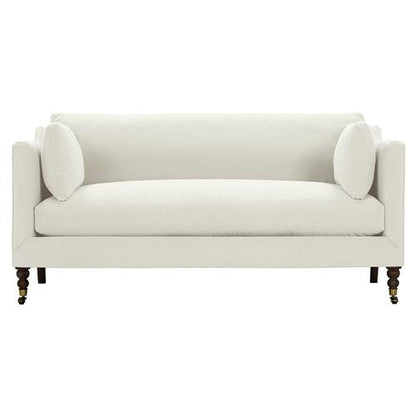 The Madeline French Grey Upholstered Brown Wood Brass Casters Nailhead Sofa Large is a contemporary masterpiece in white, featuring clean lines and two matching bolster pillows. It boasts elegant wooden legs with brass casters that add a sophisticated touch to its sleek, minimalistic design.