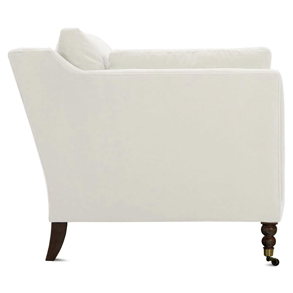 Side view of the Madeline French Grey Upholstered Brown Wood Brass Casters Nailhead Sofa Large. The sofa has a classic design with a slightly angled backrest and elegant, dark wooden legs featuring brass casters on the front two legs.