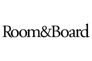 The image displays the Room & Board logo in a clean, serif font. The text is black on a white background, with the words "Room&Board" written in a single line. The ampersand symbol connects "Room" and "Board.