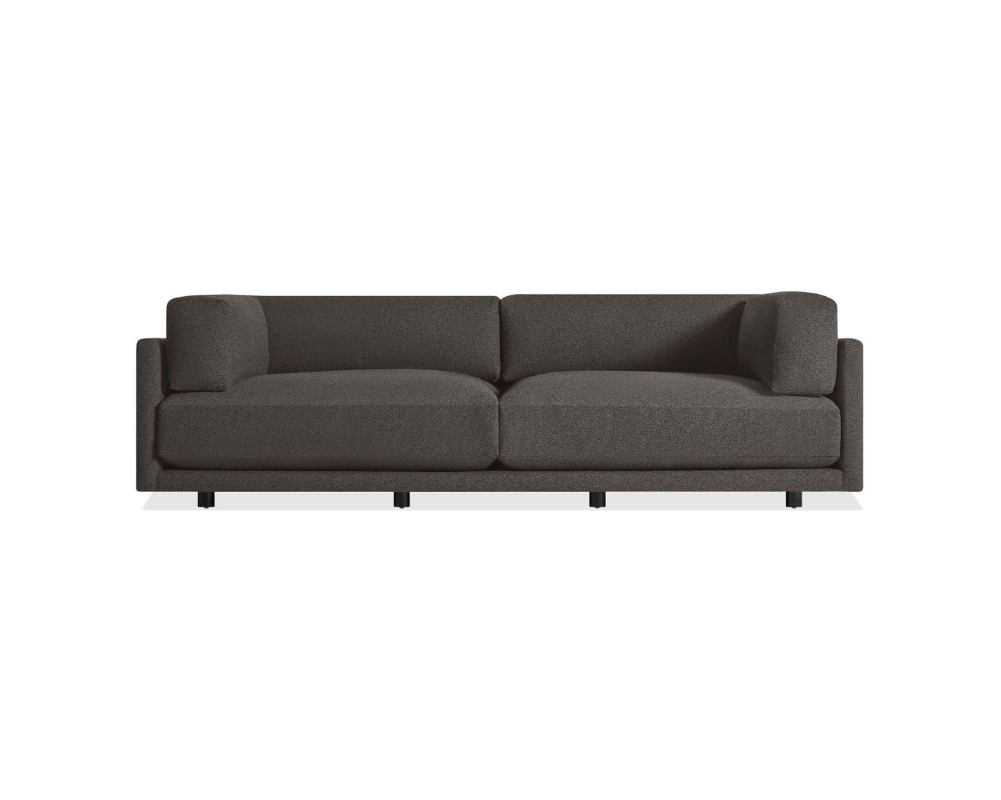 The Sunday 102-Inch Sofa is a modern piece with a minimalist design, showcasing two large cushions and a streamlined silhouette. It features low, square armrests and a simple base with short legs, all set against a plain white background in dark gray.