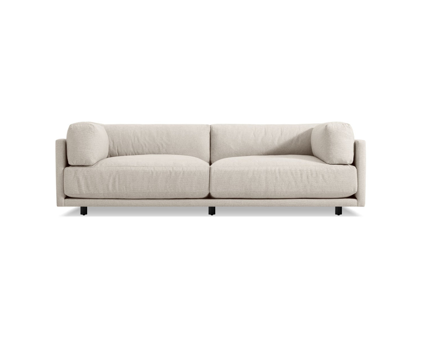 The Sunday 102-Inch Sofa is a modern piece with thick cushions and streamlined armrests set against a white background. It stands on four small, dark legs and showcases a minimalist design.