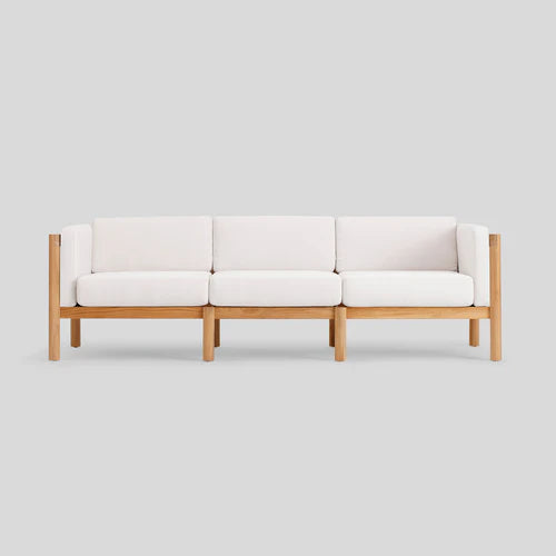 The Haven Sofa is a three-seater with a wooden frame and white cushions, set against a plain gray background.