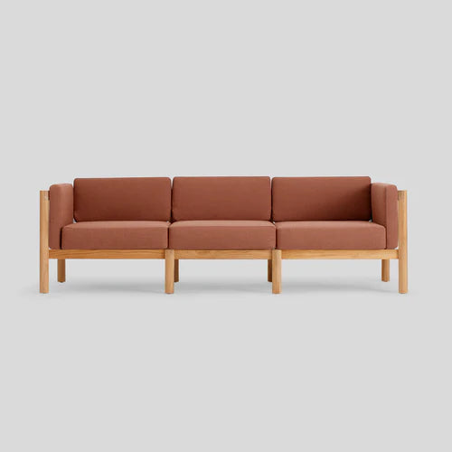 The Haven Sofa, featuring three seats with brown cushions and a light wooden frame, is set against a plain gray background.