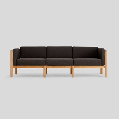 The Haven Sofa, featuring a sleek wooden frame and dark cushions, is showcased against a simple gray backdrop.