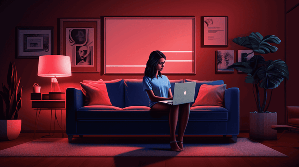 A woman sits on a blue sofa in a modern, dimly-lit room with red ambient lighting, working on a laptop. The wall behind her is adorned with framed pictures. A potted plant, side table with a lamp, and decorative pillows complete the cozy atmosphere.